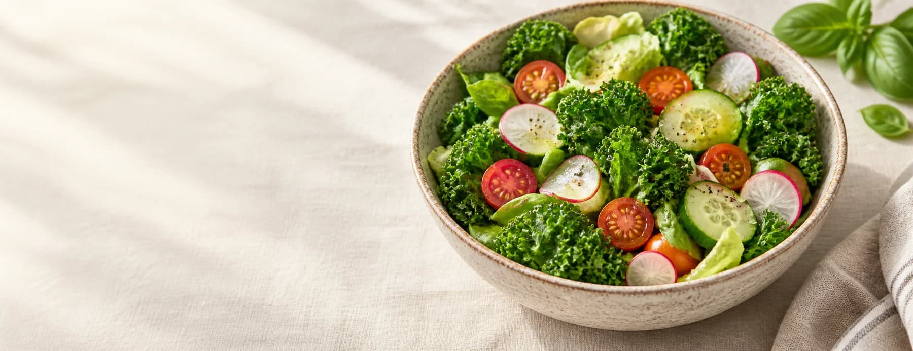 A bowl of fresh greens, tomatoes & radishes